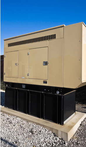 A large, stationary industrial generator set on a concrete base with a beige enclosure and a black base, against a clear blue sky.